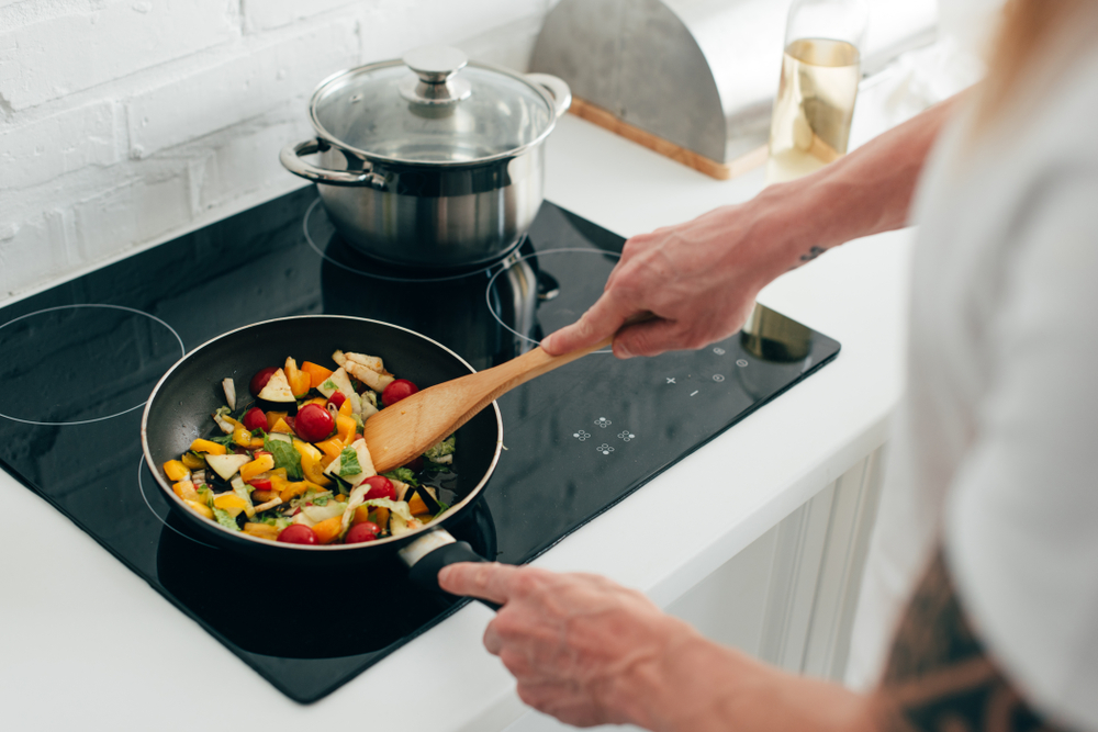 Homme faisant revenir des légumes dans une poêle